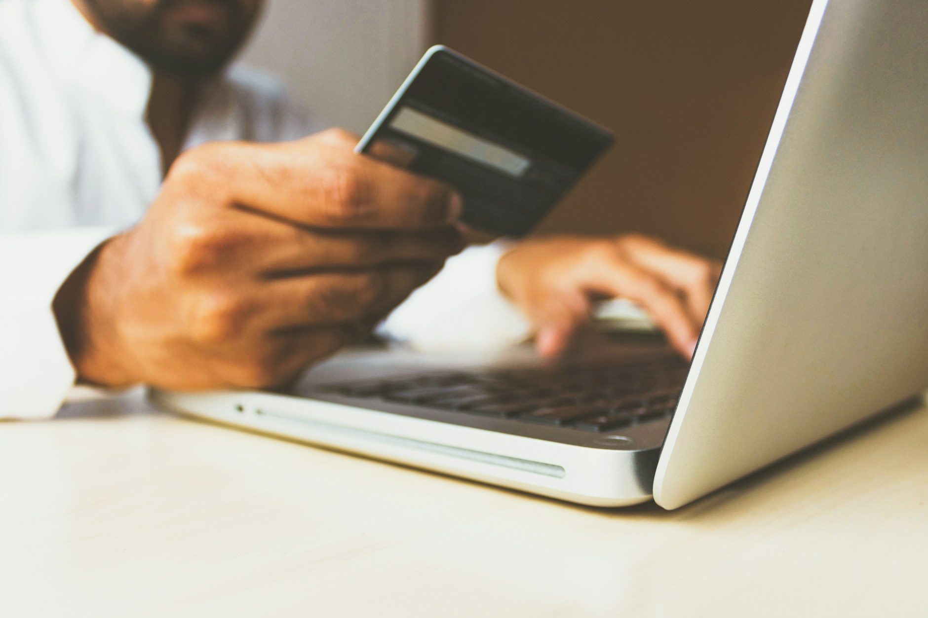 Person holding a credit card while checking their balance on a laptop.